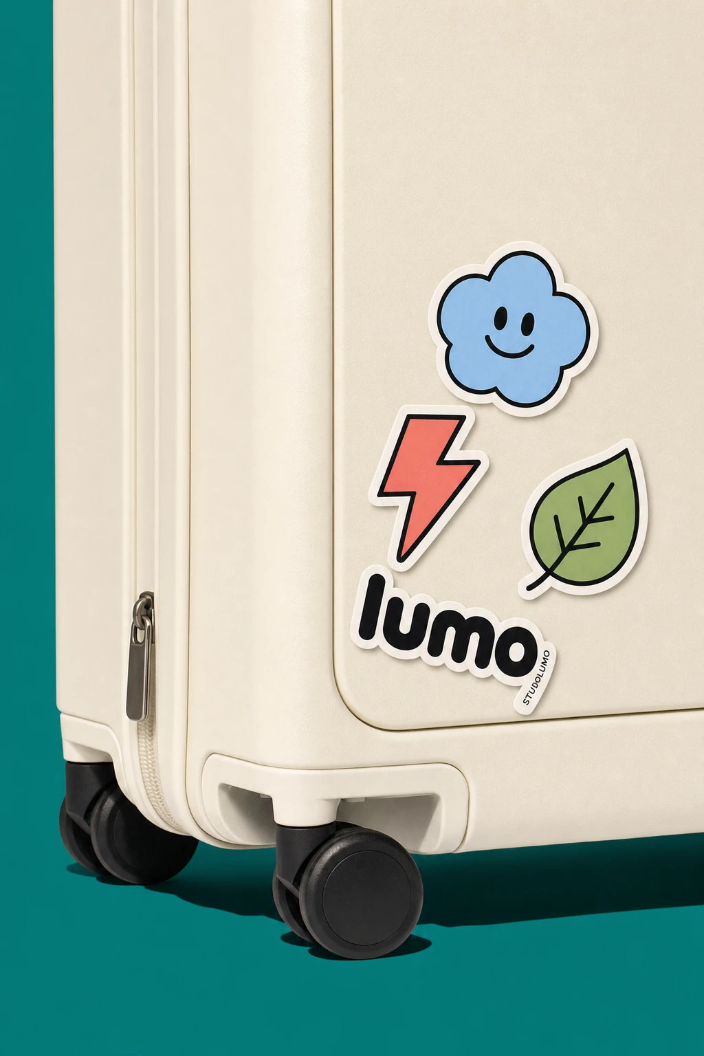 A close-up product shot of a cream-colored hardshell suitcase corner decorated with playful cartoon stickers, set against a teal backdrop.
