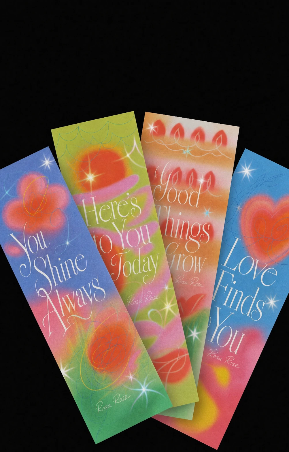 A fanned arrangement of four tall vertical bookmark cards with airbrushed gradient art and elegant uplifting hand-lettered phrases, set against a black backdrop