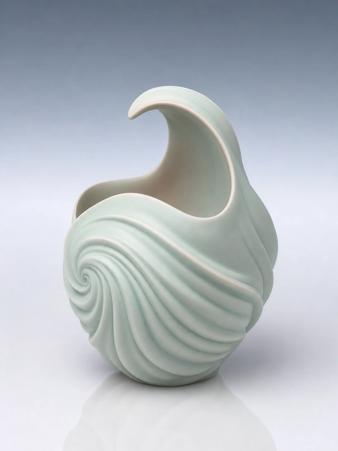 A studio photograph of an elegant celadon-glazed ceramic vessel with a sculptural wave-like form.