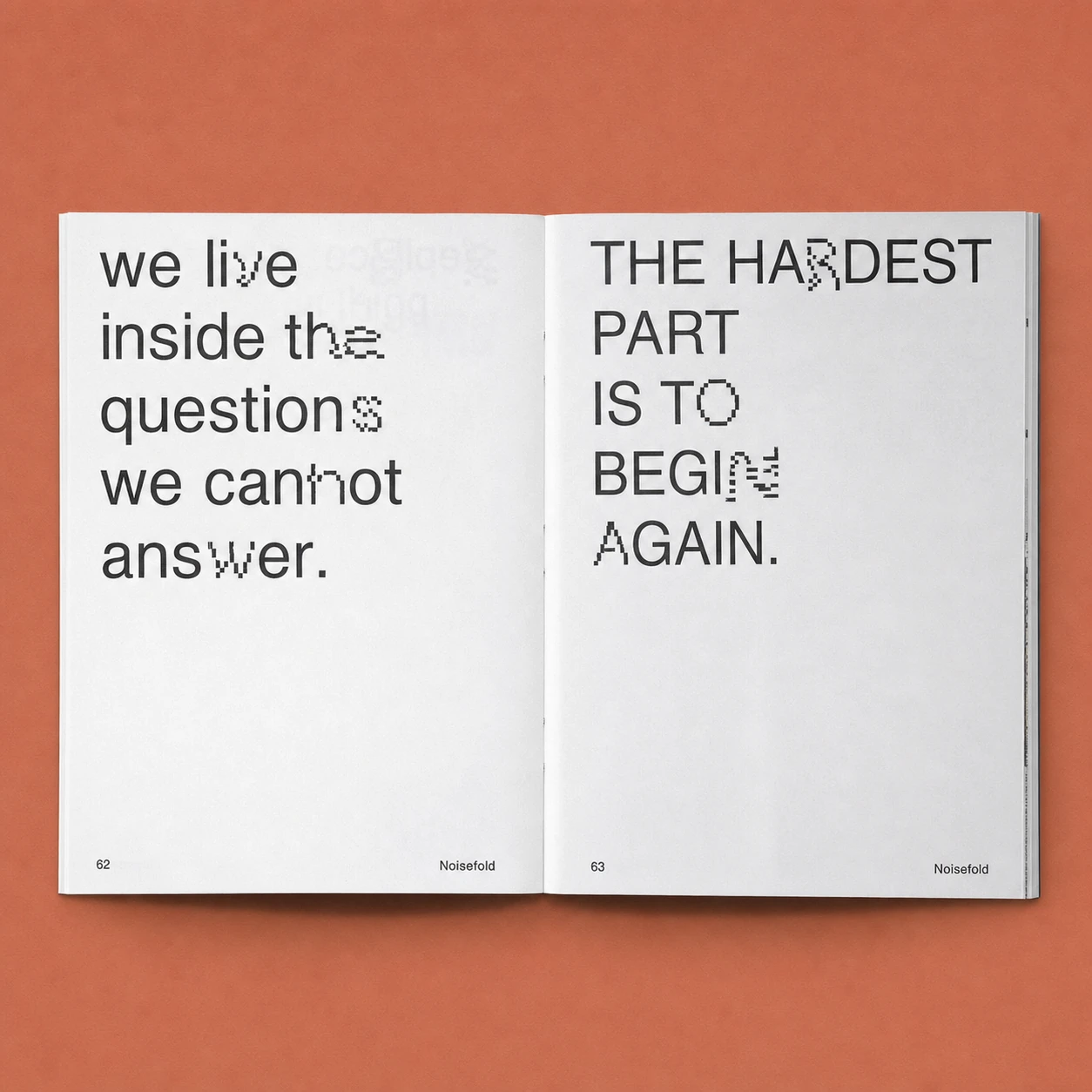 An open art book photographed flat on a warm terracotta surface, with bold black typographic statements glitching into pixelated distortion across two facing pa