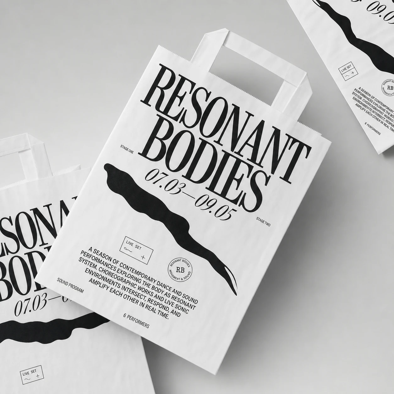 A black-and-white branded paper shopping bag mockup printed with bold editorial typography for a contemporary performance event.