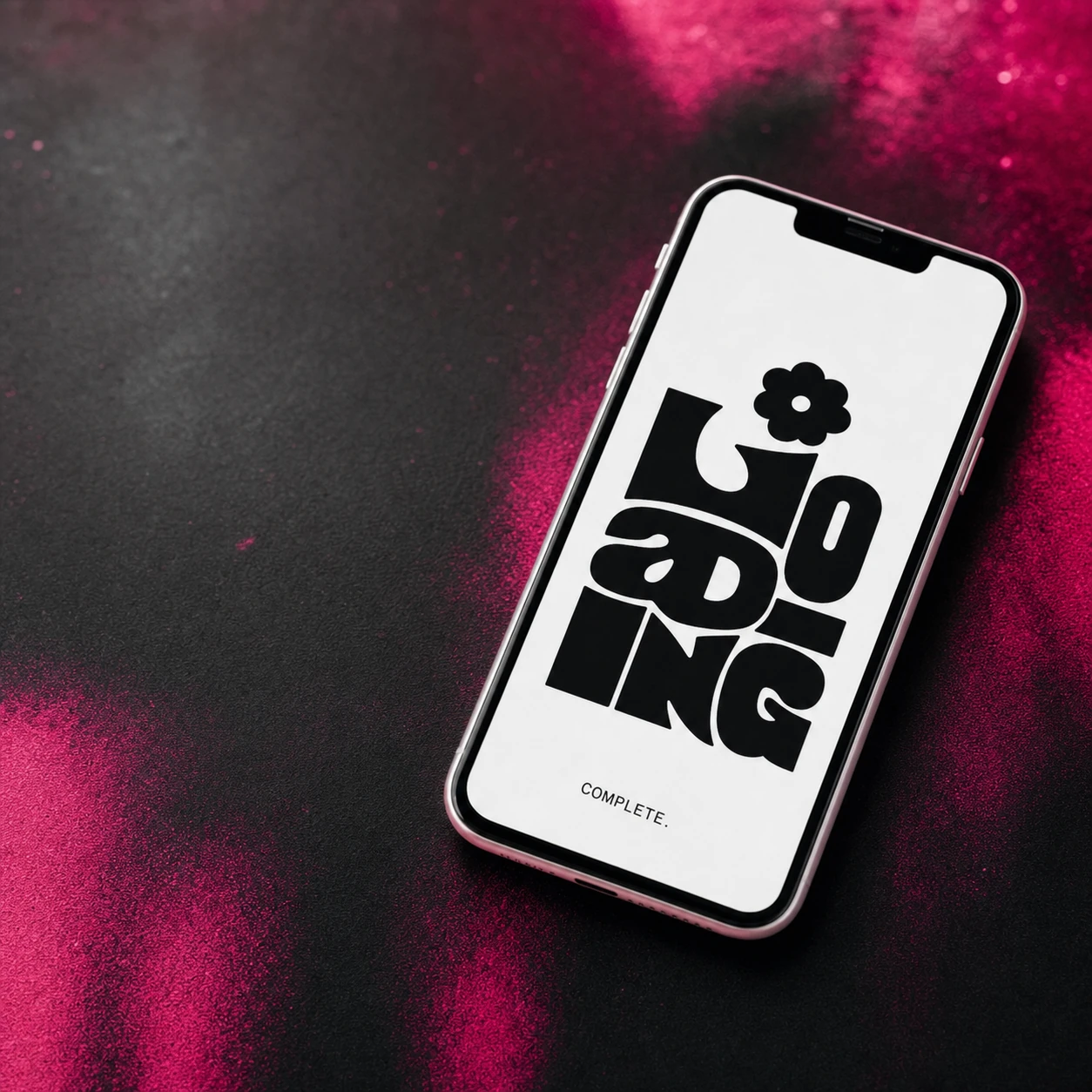 A smartphone resting on a textured pink-and-black surface, its white screen displaying bold playful black display typography.