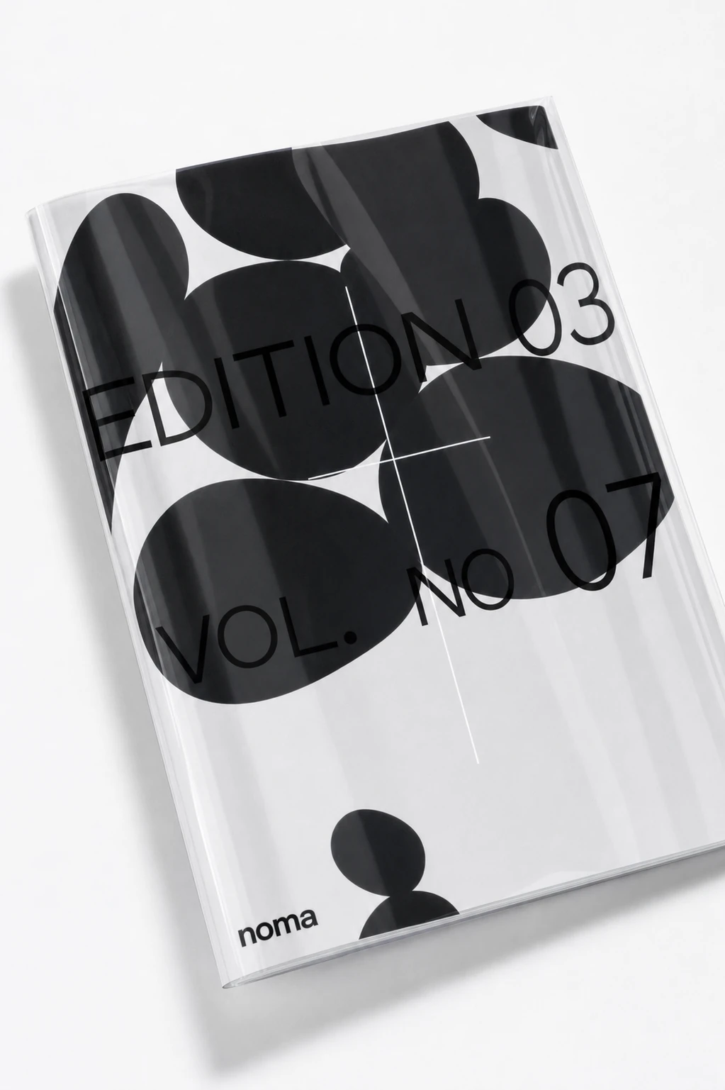 A minimalist editorial book cover photographed at an angle, featuring overlapping black organic blobs with bold sans-serif typography on a glossy white surface.