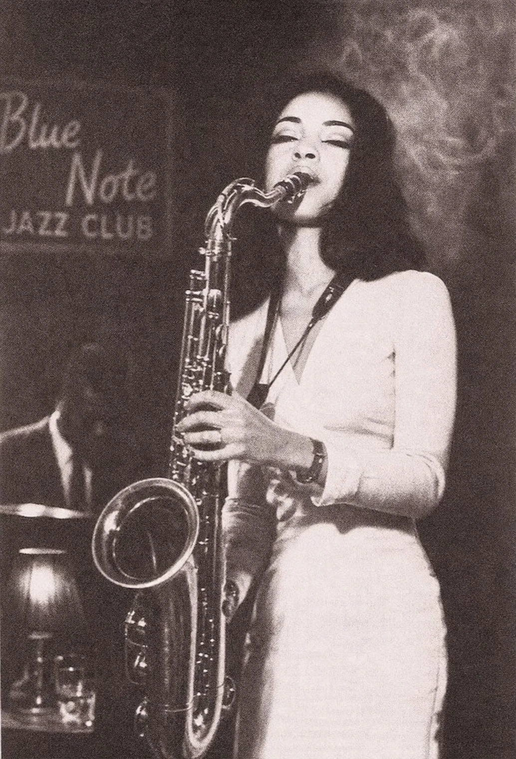 A vintage sepia-toned photograph of a woman playing tenor saxophone on stage at an intimate jazz club.