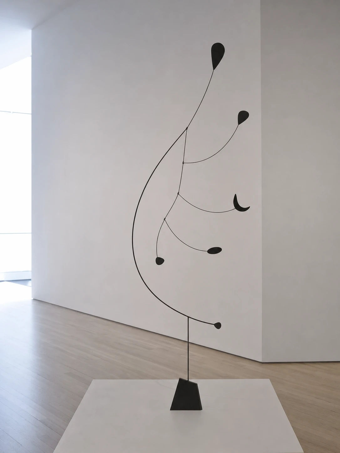 A minimalist black abstract standing mobile sculpture displayed in a bright, sparse white gallery space.