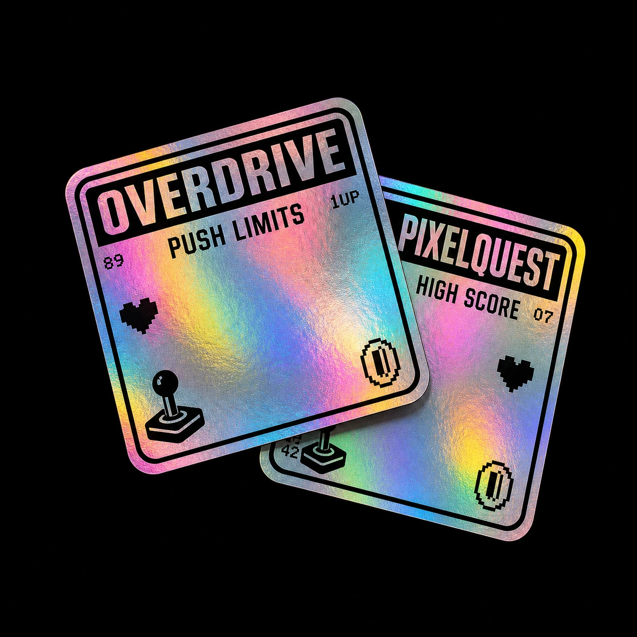 Two overlapping square holographic stickers with retro-arcade themed black graphics, photographed on a black background.