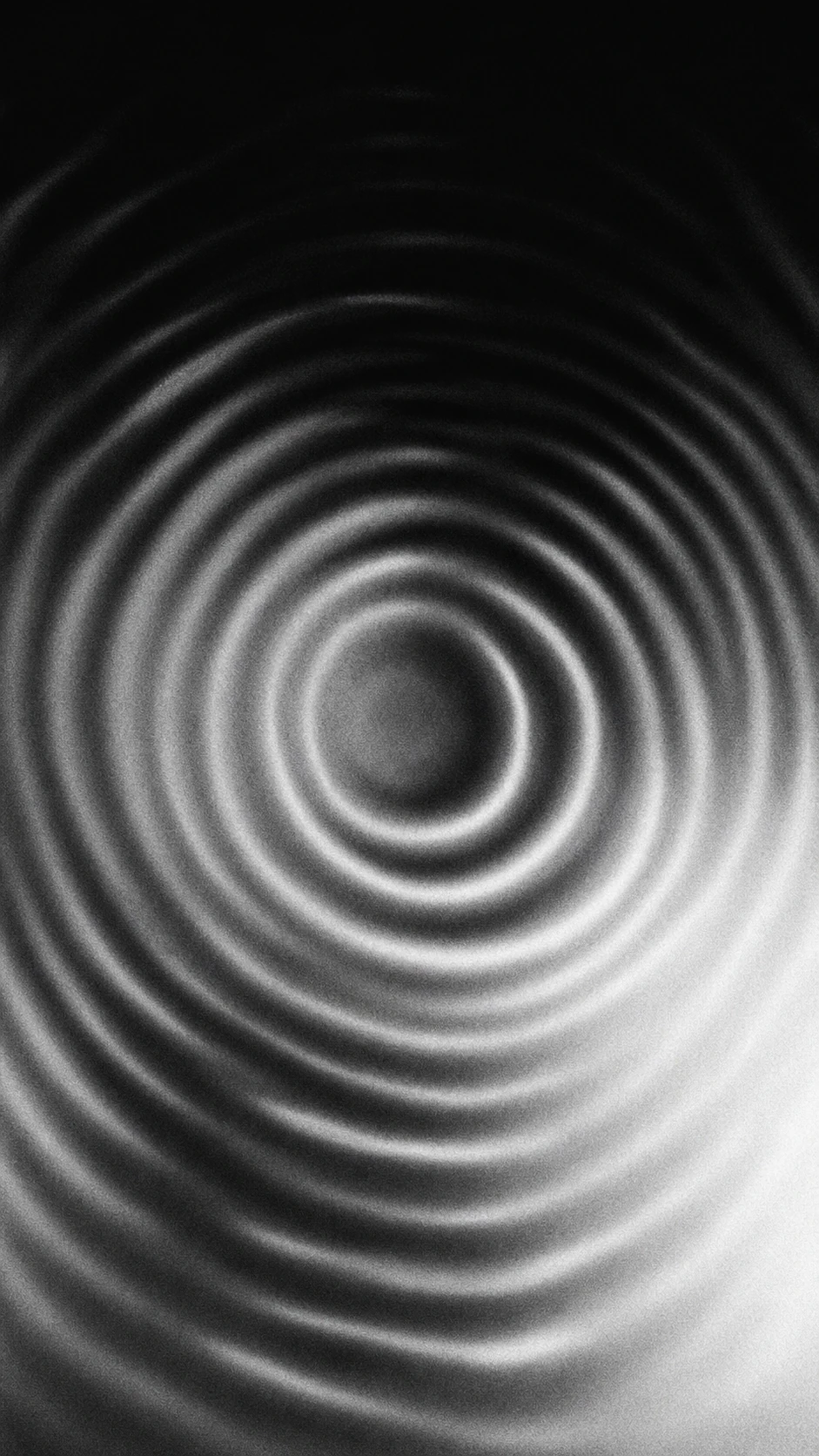 A monochrome abstract of concentric ripple waves radiating from an off-center point, like vibrations on a fluid surface.