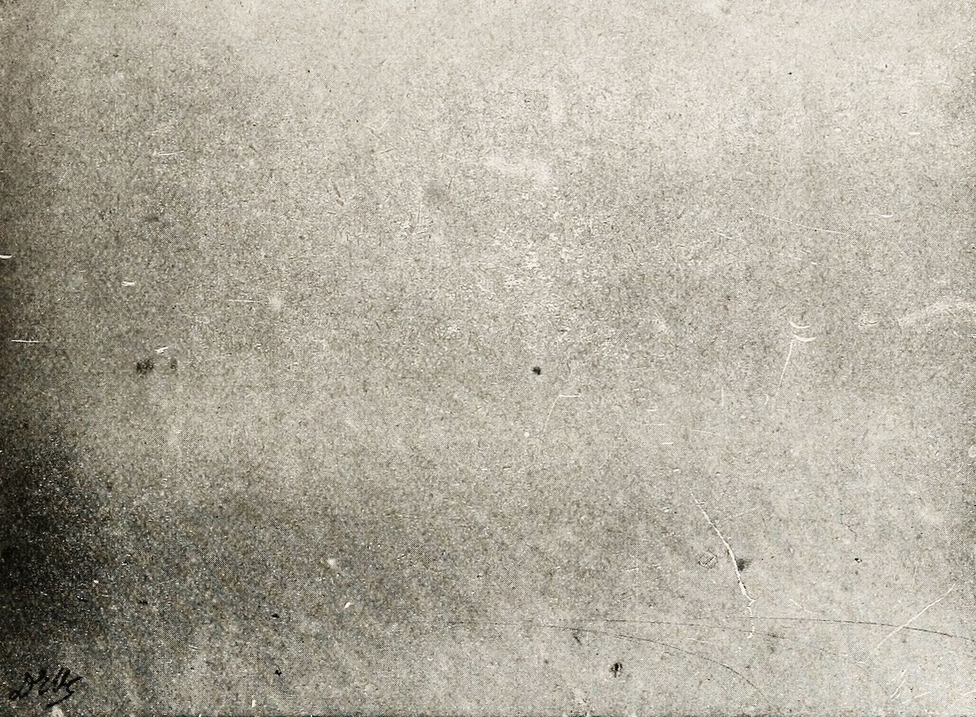 Close-up of a grainy, distressed surface with scratches and speckles.