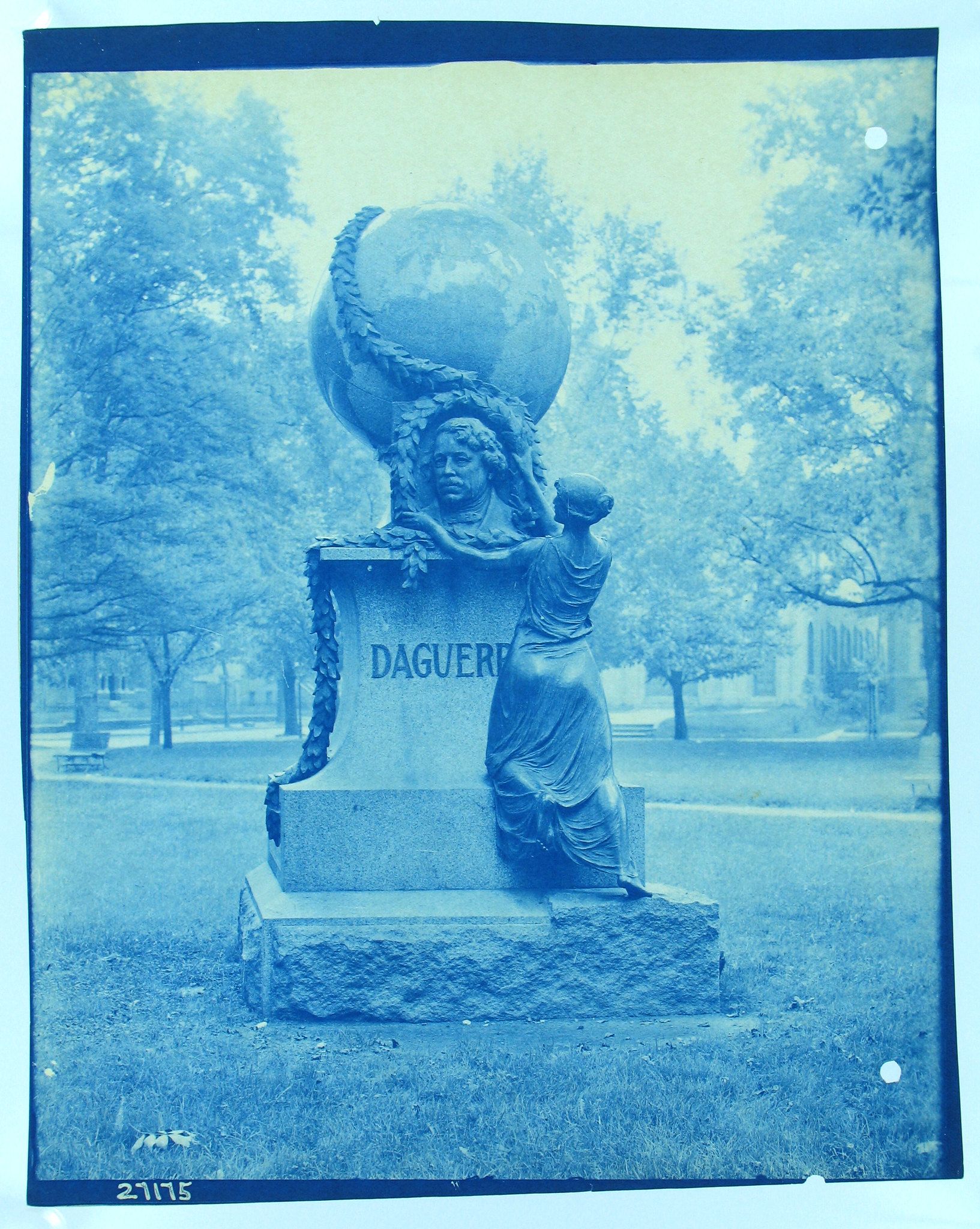 Vintage cyanotype photograph of a statue and tombstone in a park-like setting.