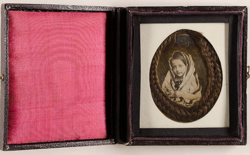 Antique case open, revealing a sepia-toned portrait of a young child inside.