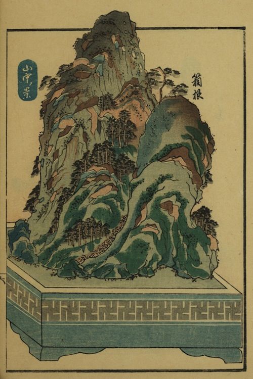Vintage woodblock print of a lush green mountain landscape with Japanese text and a patterned base.