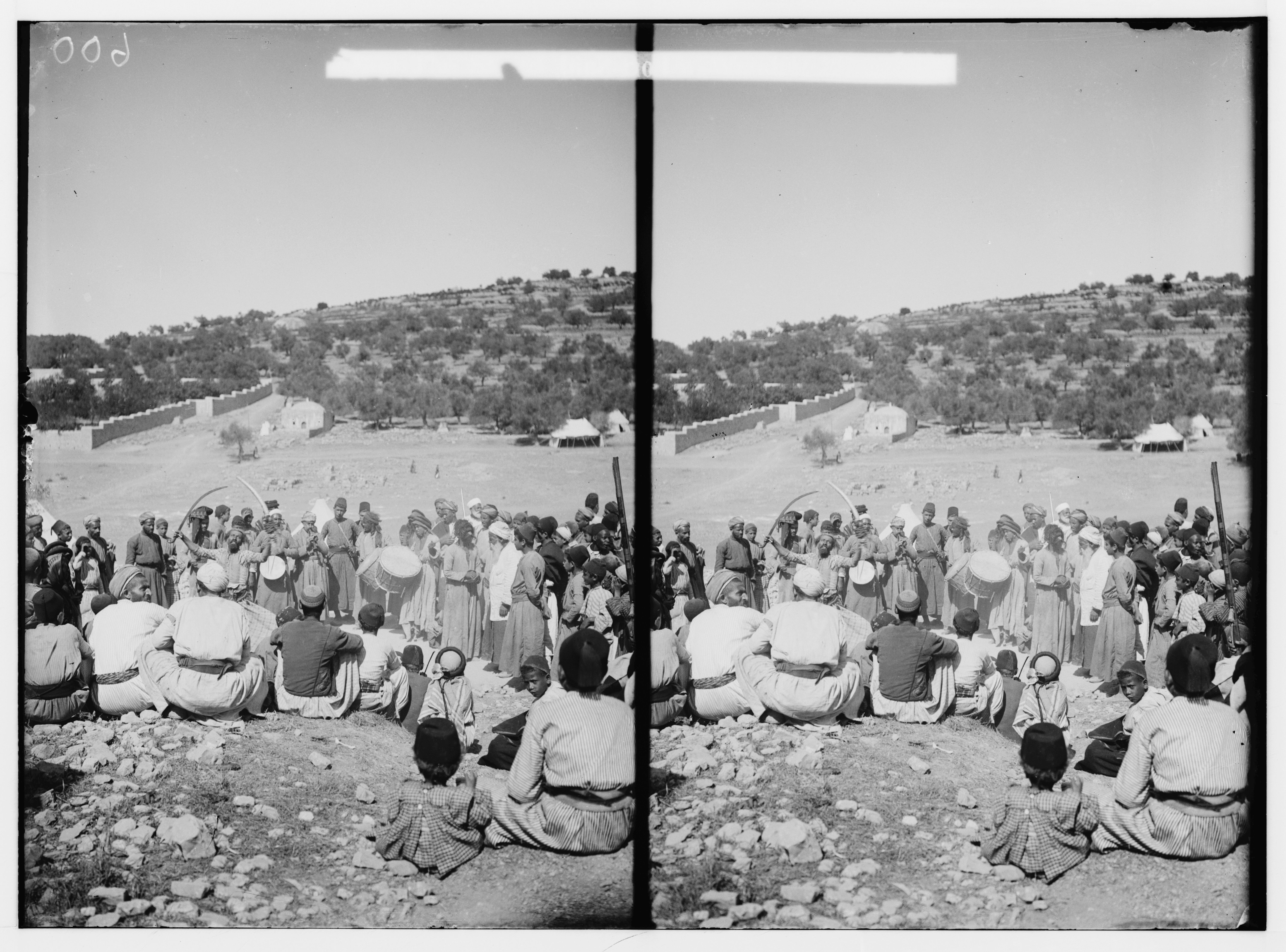 Stereoscopic photograph of a large group of people gathered in a circle in a hilly landscape.