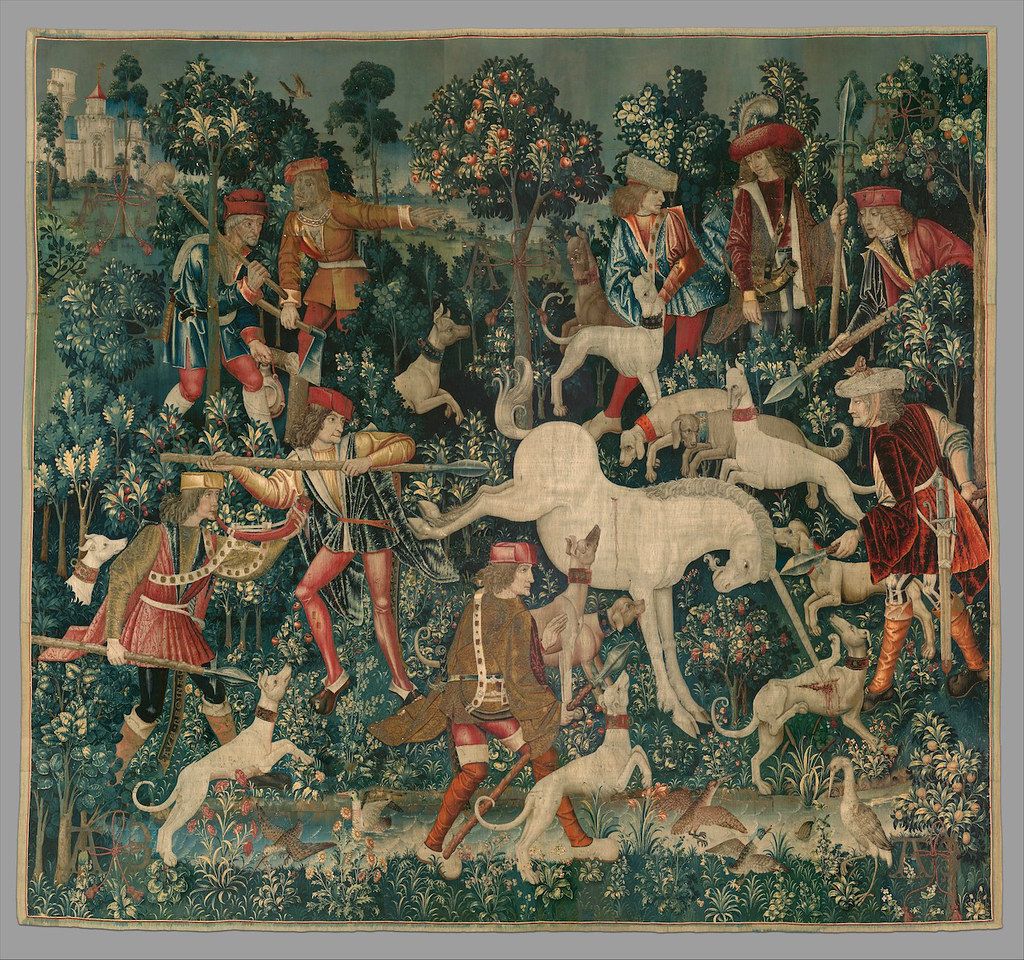 A detailed tapestry depicting a hunting scene with hunters pursuing a unicorn in a lush forest.