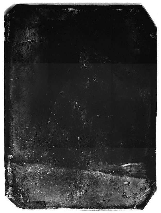 A vintage, heavily damaged black and white photograph with scratches, blemishes, and a grainy texture.