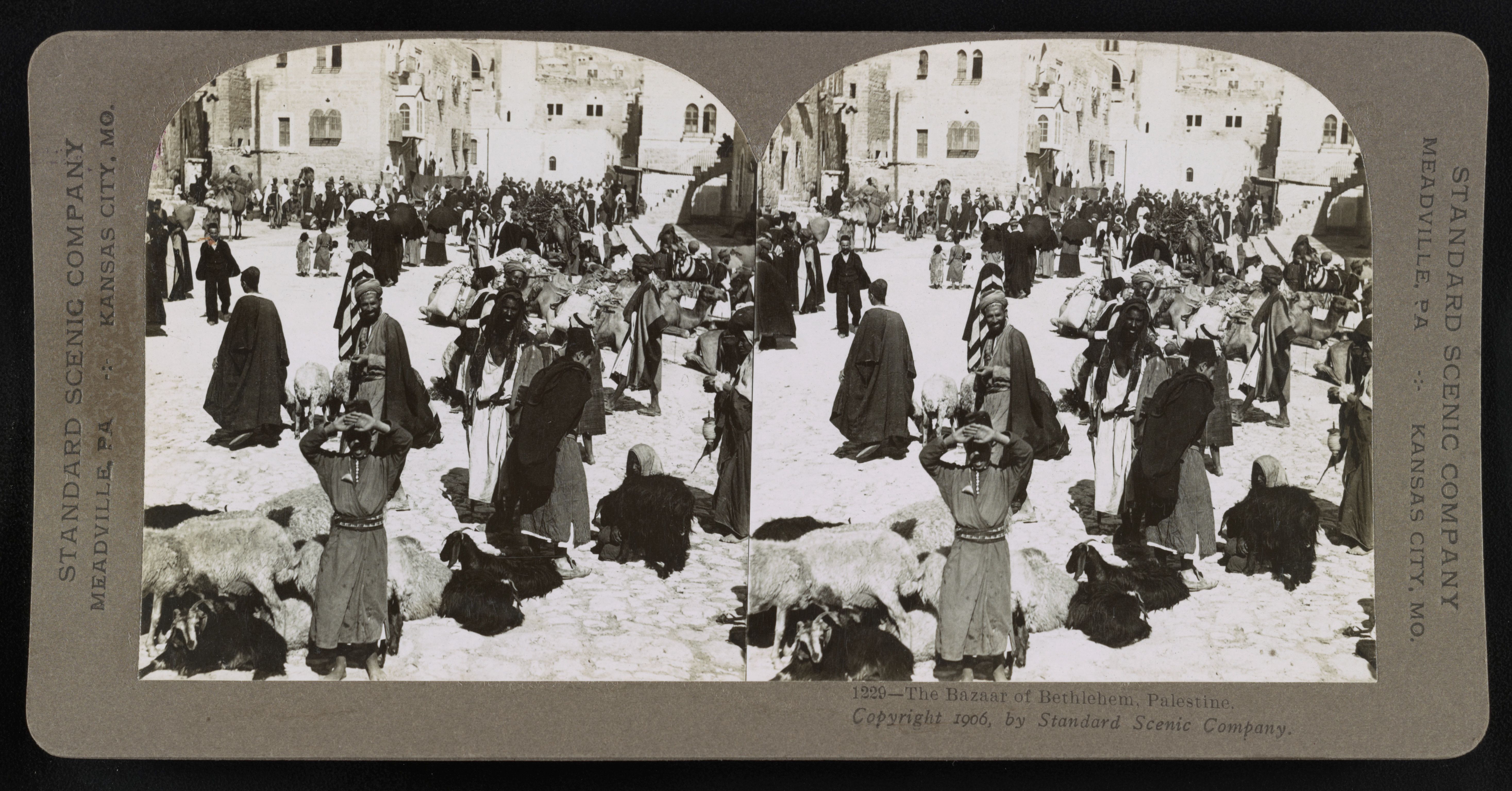 Stereoscope card of the Bazaar of Bethlehem, Palestine, 1906. A crowded market scene with people in traditional clothing and stone buildings in the background.