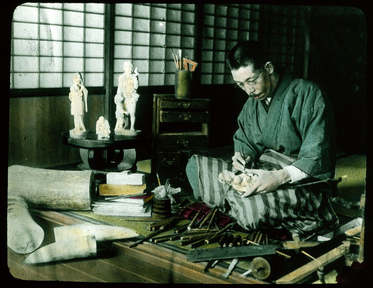 A Japanese artisan working on a sculpture in a traditional room.