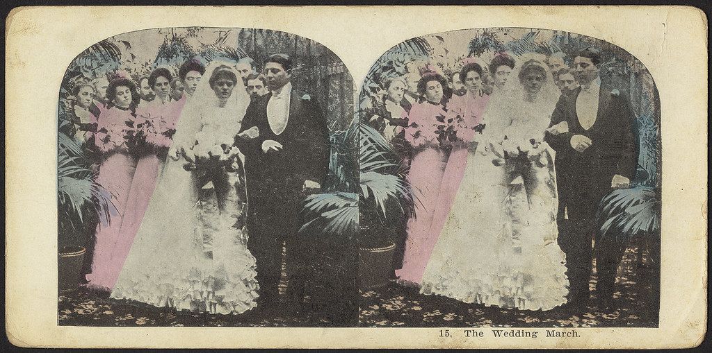 Stereoscope card of a wedding scene with a bride and groom surrounded by bridesmaids and groomsmen.
