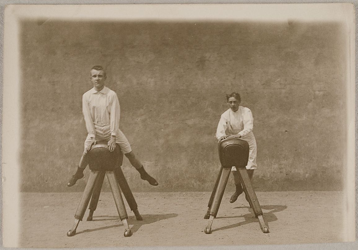 Two boys sitting on hobby horses in a sepia-toned photograph.