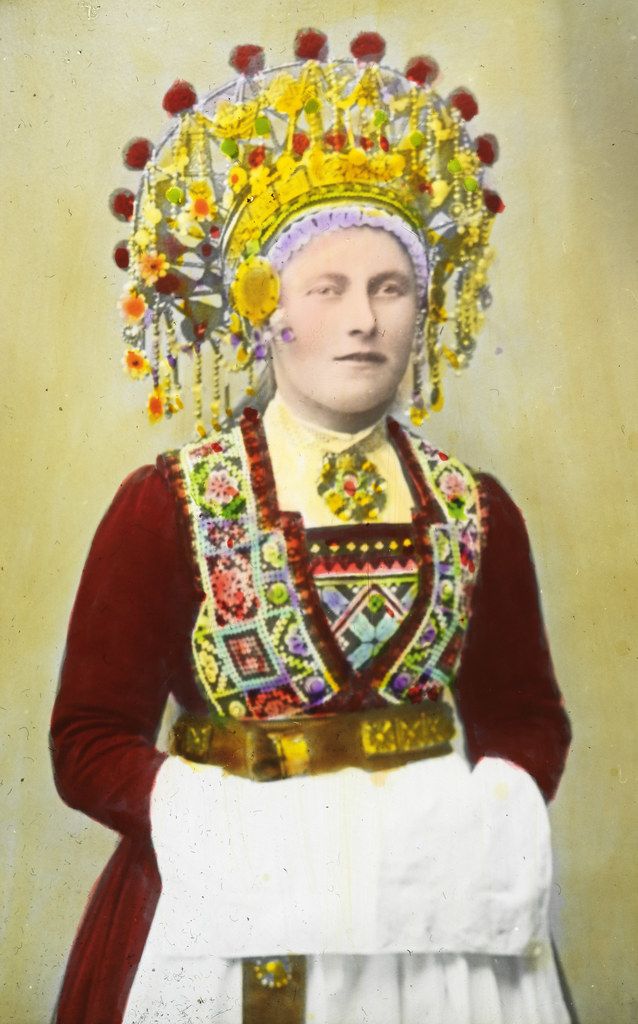 Vintage hand-colored portrait of a woman in traditional folk costume with elaborate headgear and embroidered dress.