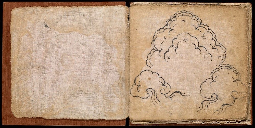 Open book with a blank page on the left and a delicate ink drawing of stylized clouds on the right.