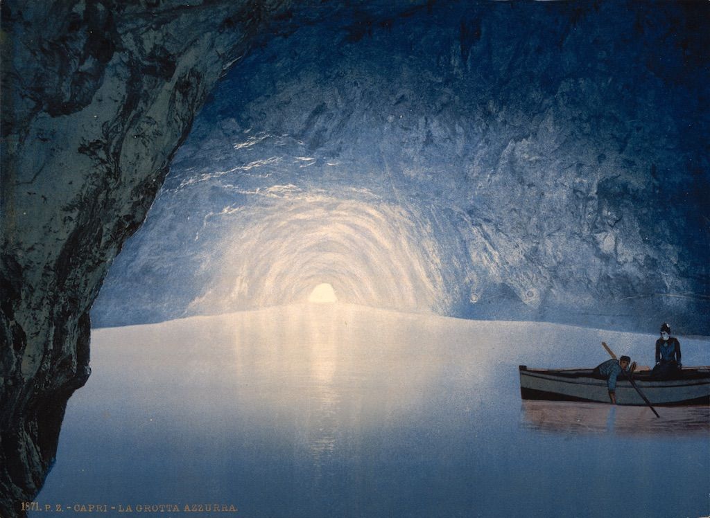 Interior of the Blue Grotto in Capri, Italy, with a small rowboat and two figures.