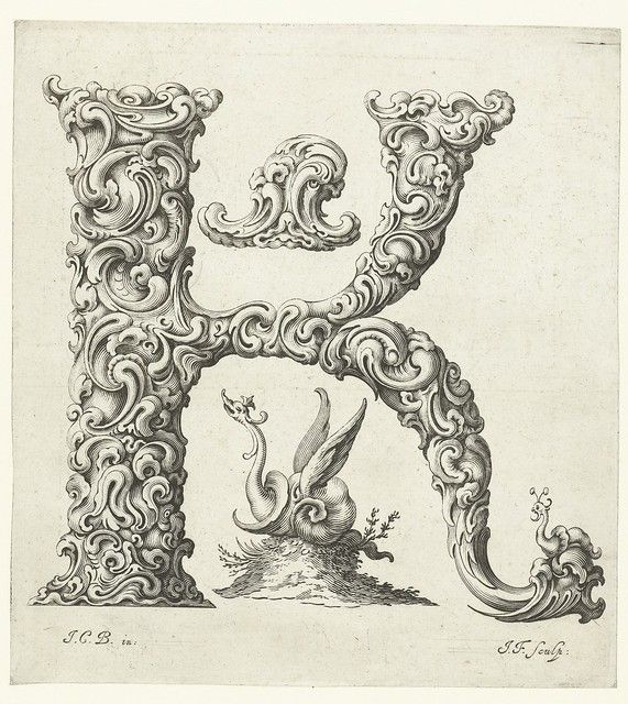 An ornate letter 'K' with a swan in distress within its open space.