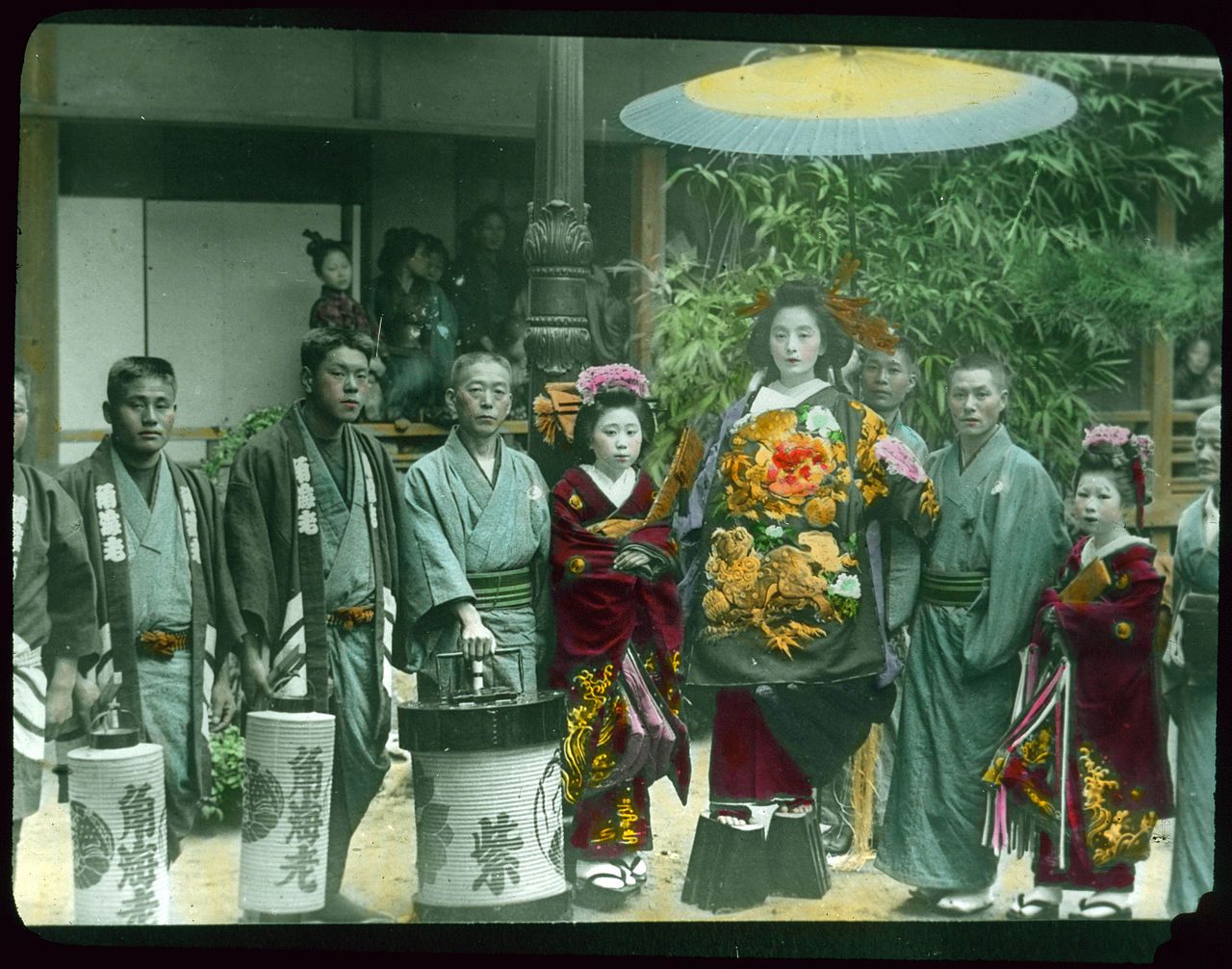 A color photograph of a traditional Japanese wedding procession with a bride in a red kimono surrounded by attendants and family members.
