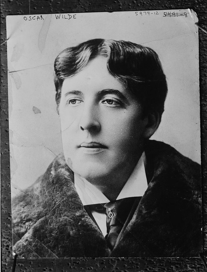 Black and white portrait of Oscar Wilde in a formal suit.