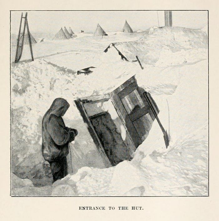 A black and white illustration of a person standing near the entrance to a hut in a snowy landscape.