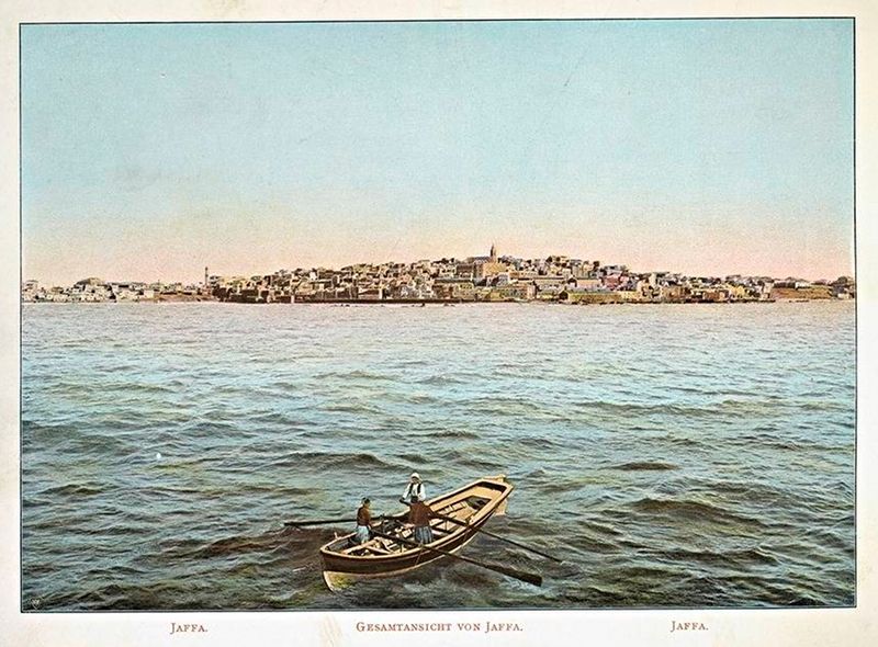 Vintage postcard of Jaffa, Israel, showing a boat on the water with the city skyline in the background.