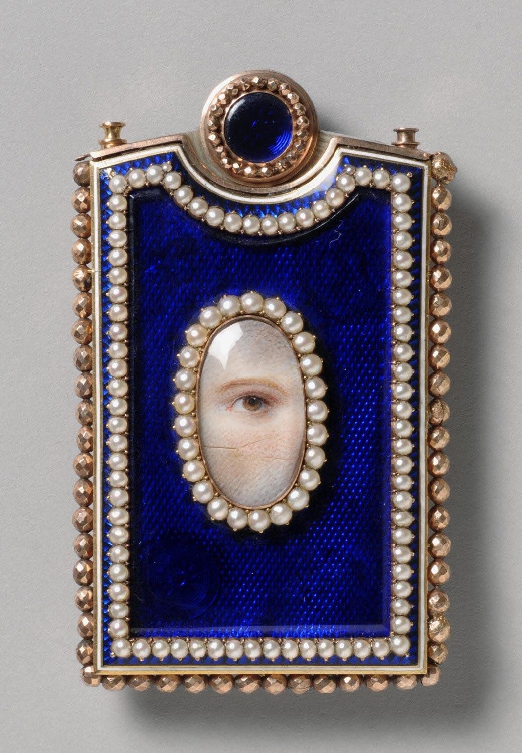 Close-up of a rectangular pendant with a portrait of a human eye.