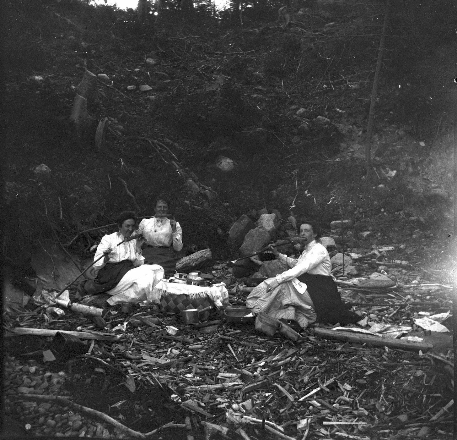 A vintage black and white photograph of a picnic in a forest.