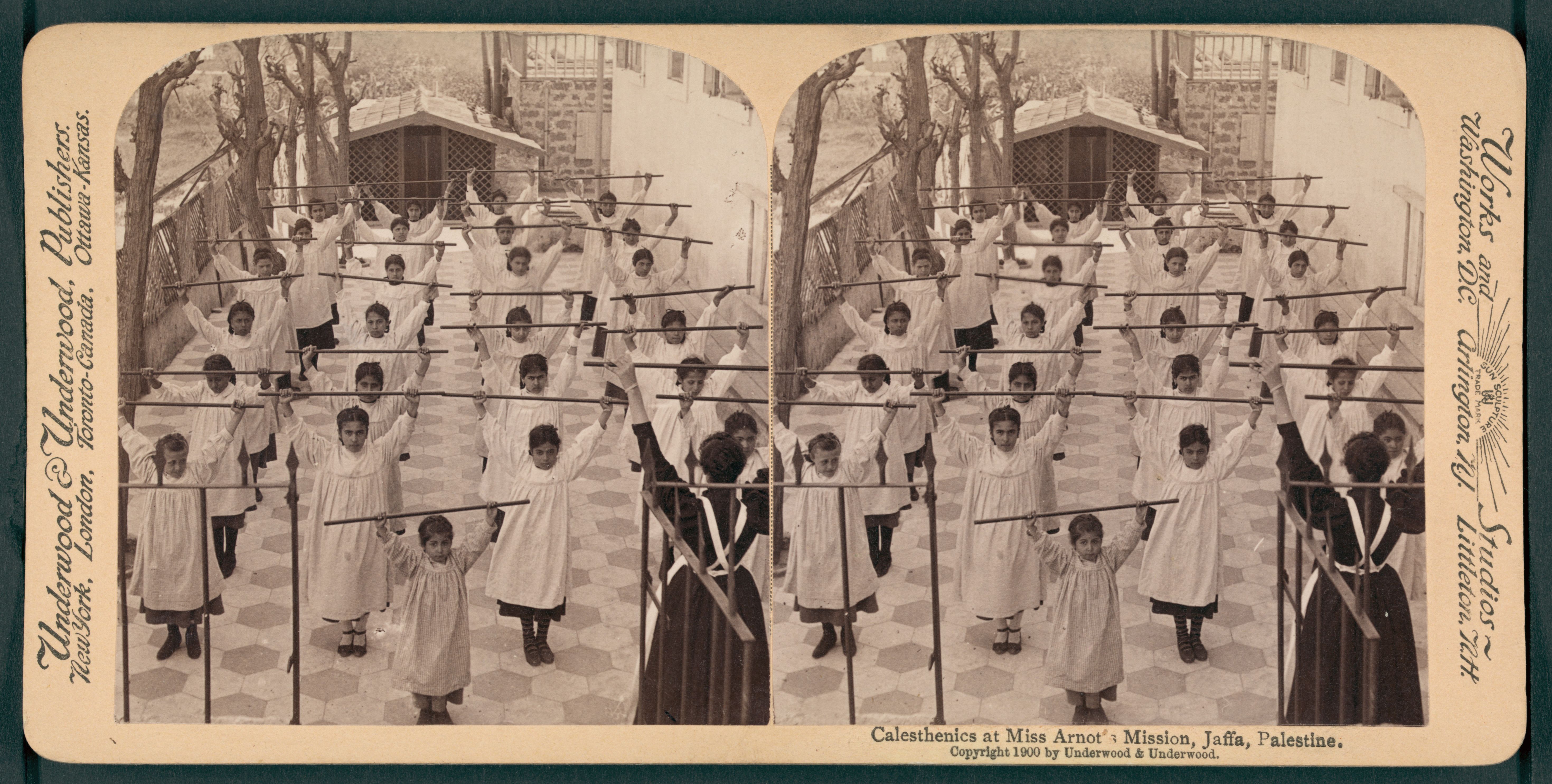 Stereoscopic photograph of a group of students performing calisthenics at a mission in Jaffa, Palestine.