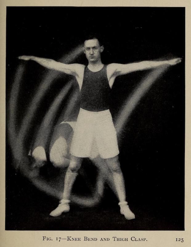 Vintage photograph of a man performing a gymnastic exercise, bending his knee and clasping his thigh, with motion blur indicating movement.