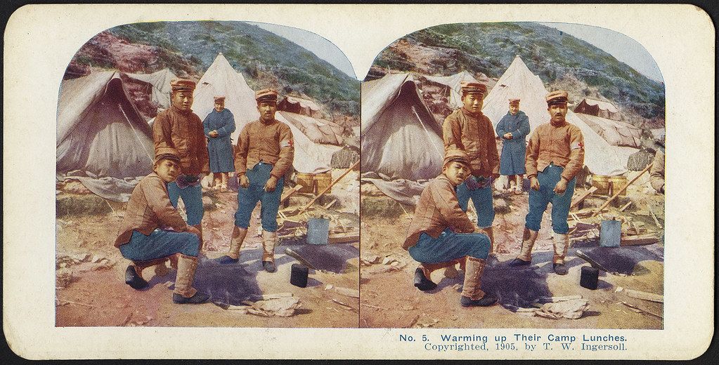 Stereoscopic photograph of four soldiers warming up their lunches in a camp setting, 1905.