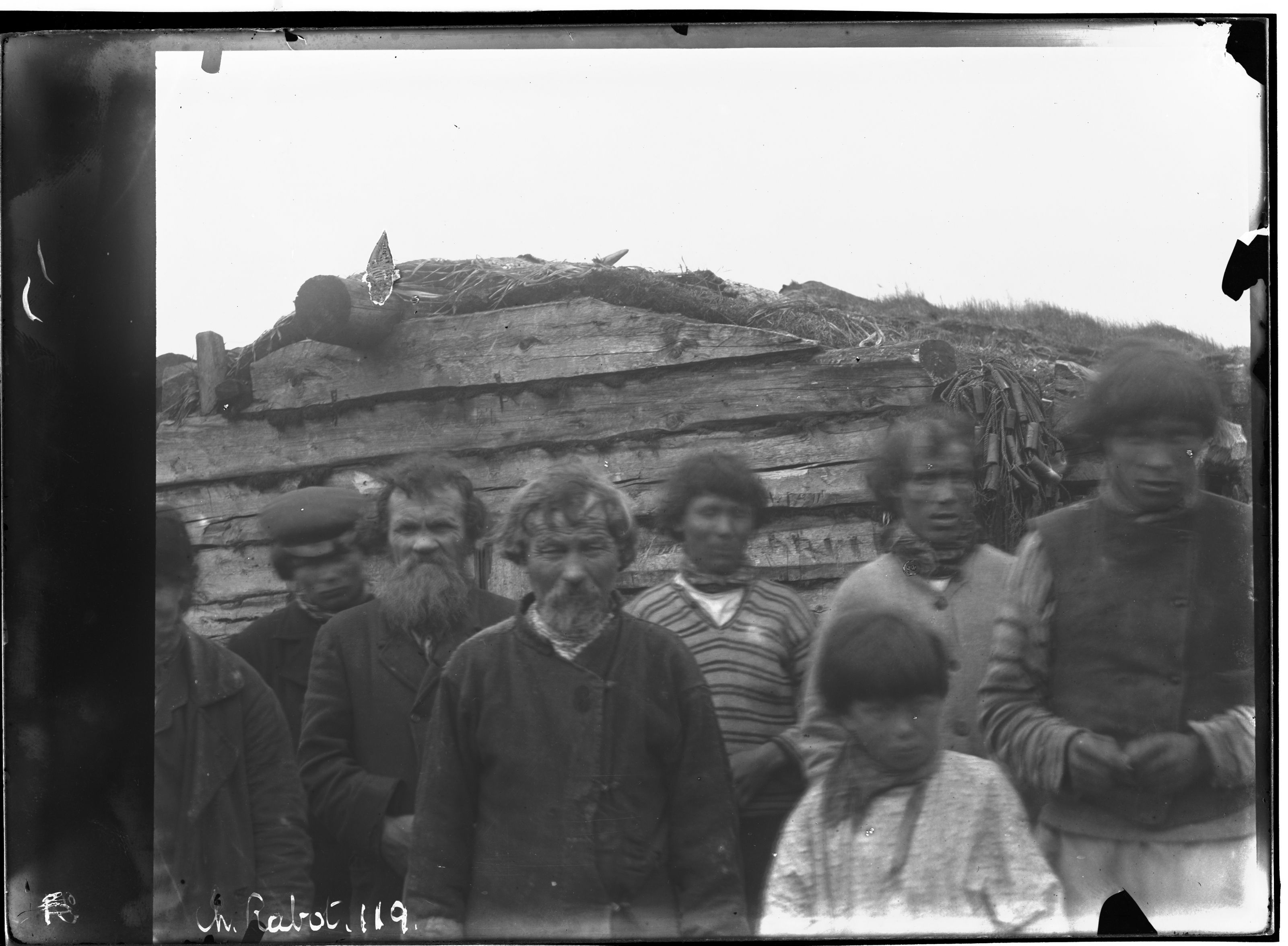 A black and white photograph of a group of people standing in front of a hill of debris and ruins.