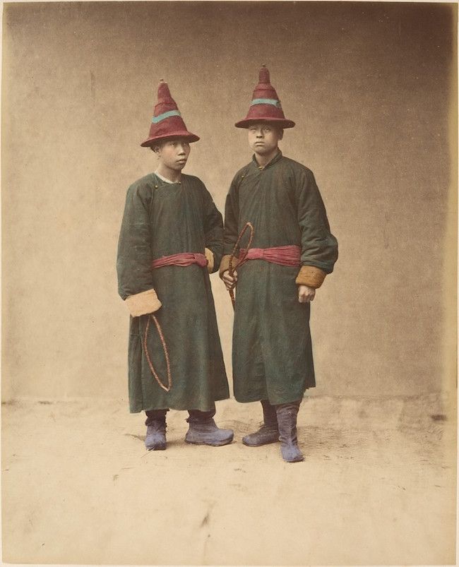 Two young men in traditional clothing standing side-by-side in a studio portrait.