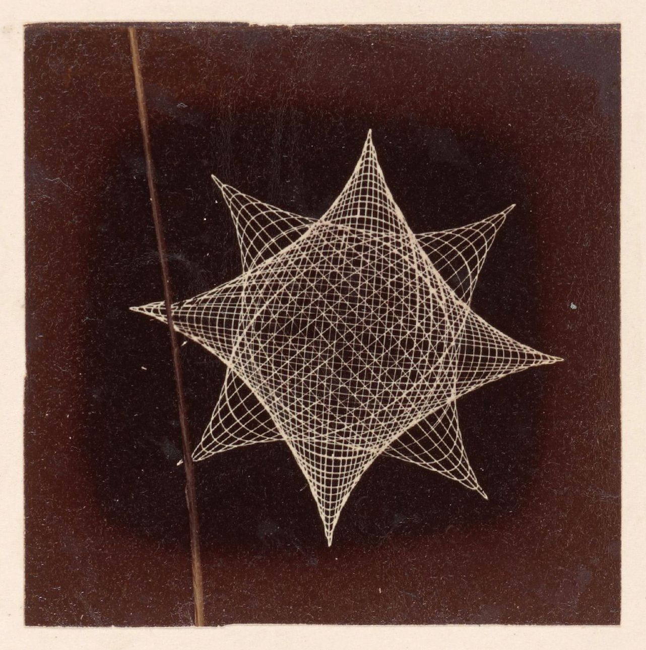 A vintage photograph of a complex geometric shape resembling a star, constructed from a network of thin, intersecting lines against a deep black background.