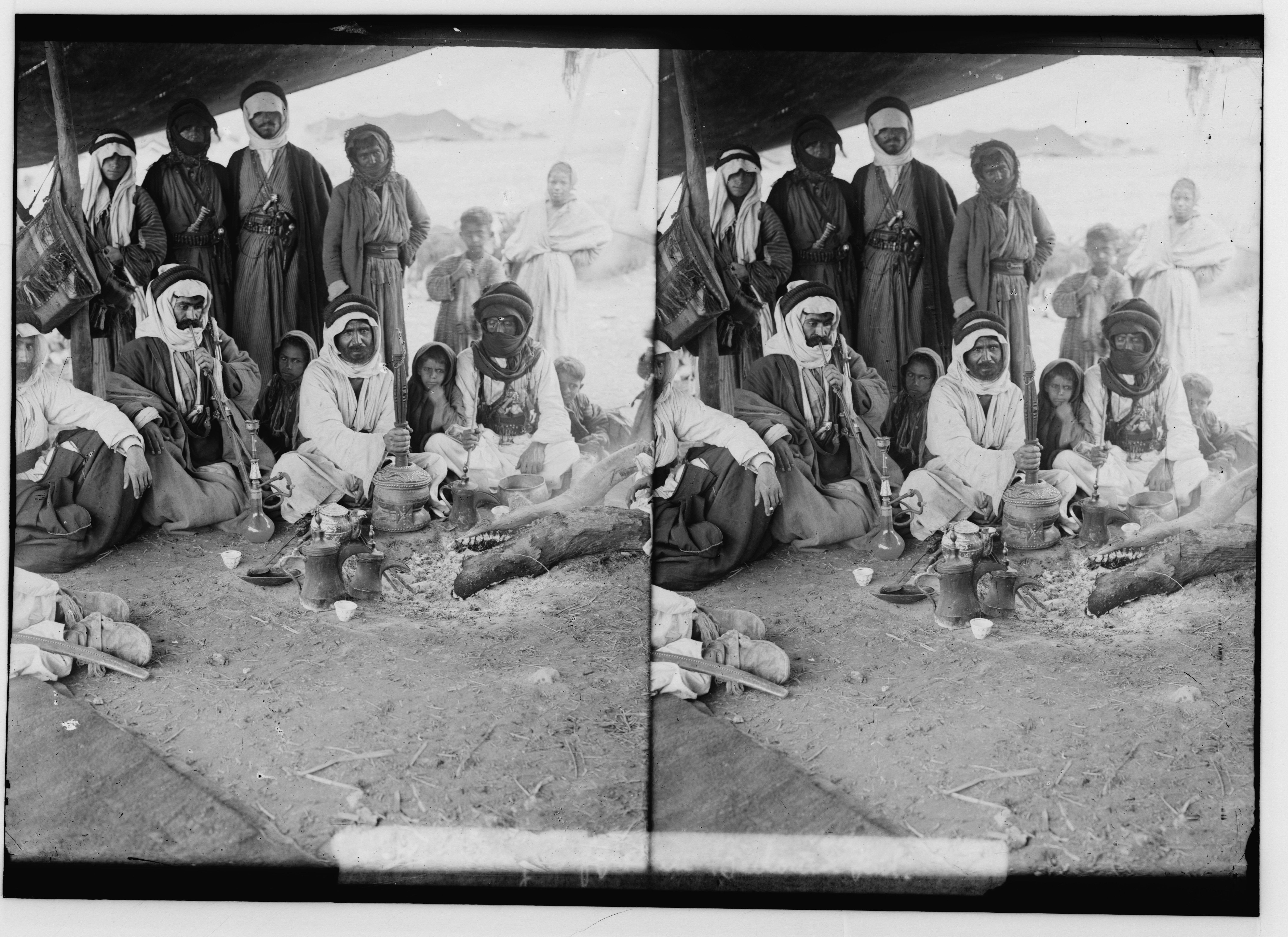 Stereoscopic photograph of a group of people in traditional clothing gathered in a desert setting.