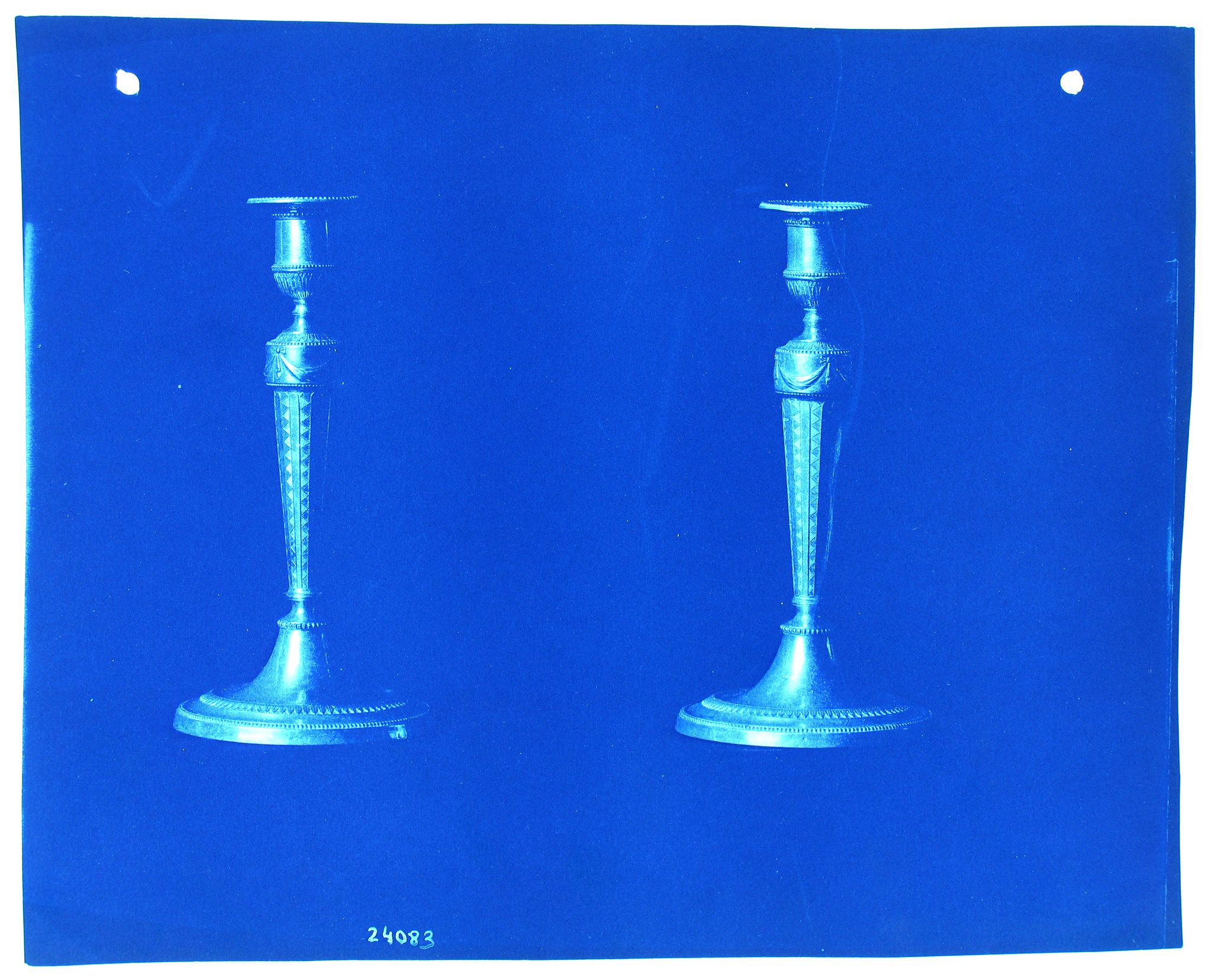 Two antique candlesticks against a blue background.
