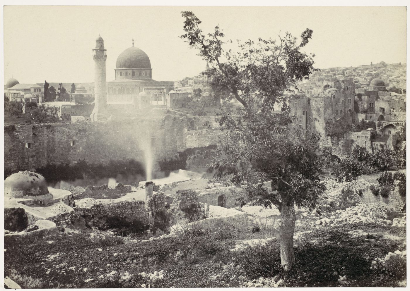 Vintage black and white photograph of Jerusalem with the Dome of the Rock and ruins in the foreground.