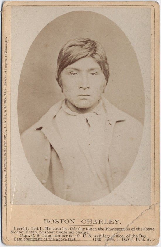 Vintage sepia-toned photograph of Boston Charley, a Modoc Indian prisoner, wearing a dark jacket and vest, with text at the bottom certifying the photograph's authenticity.