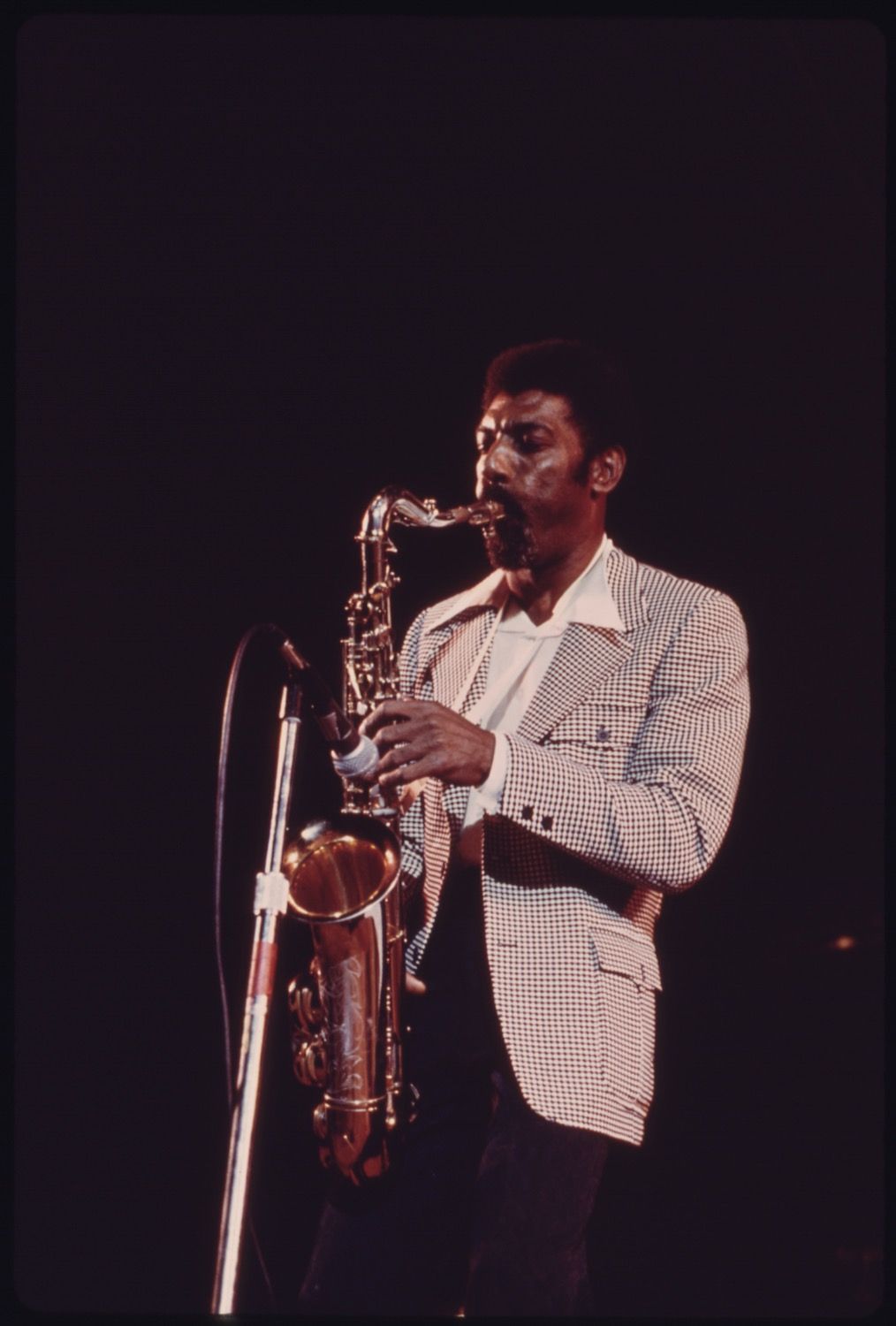 A man playing a saxophone on a dark stage.