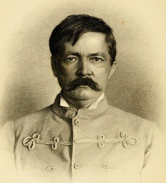 Vintage sepia-toned portrait of a man with a large mustache wearing a decorated jacket.