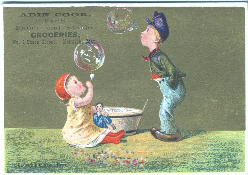 Vintage trade card featuring two children playing with bubbles in a grassy field, advertising Adin Cook's grocery store.