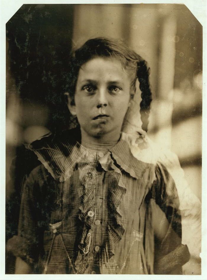 A sepia-toned vintage photograph of a young girl in a high-collared dress.