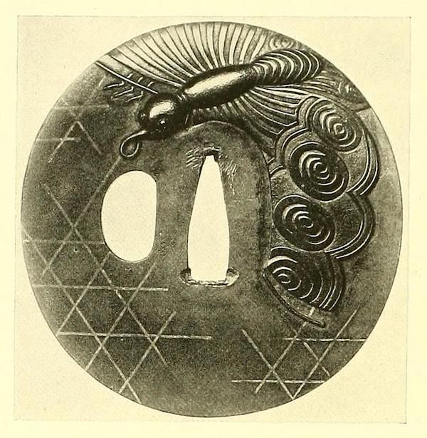 A detailed, circular tsuba (a Japanese sword guard) with a peacock design and geometric pattern.