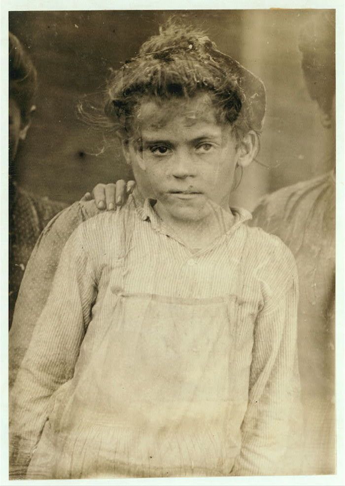 A vintage black and white photograph of a young child with dark curly hair and a solemn expression.