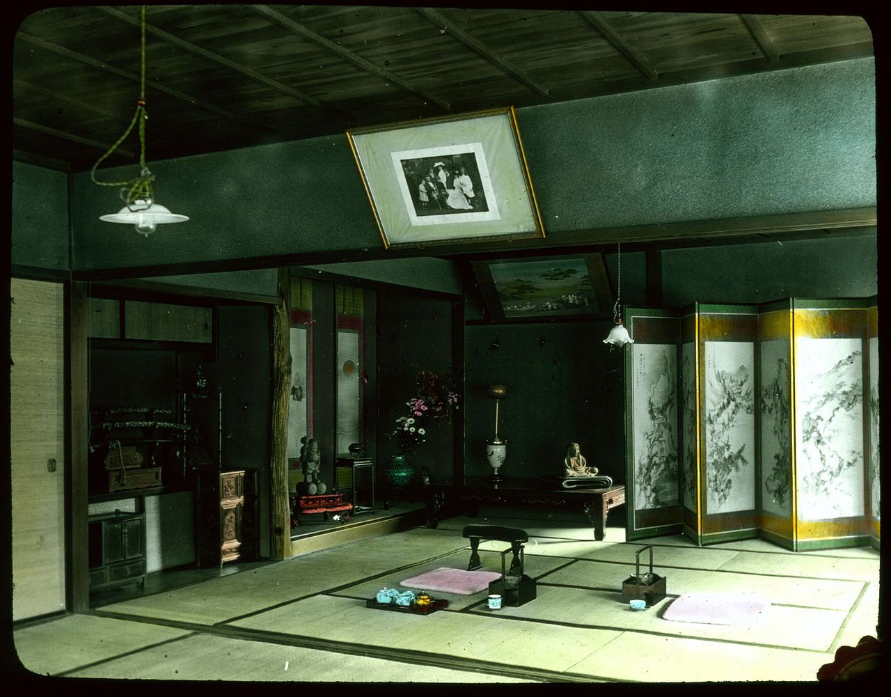 Interior of a traditional Japanese room with dark wood paneling, tatami mat floor, and decorative objects.