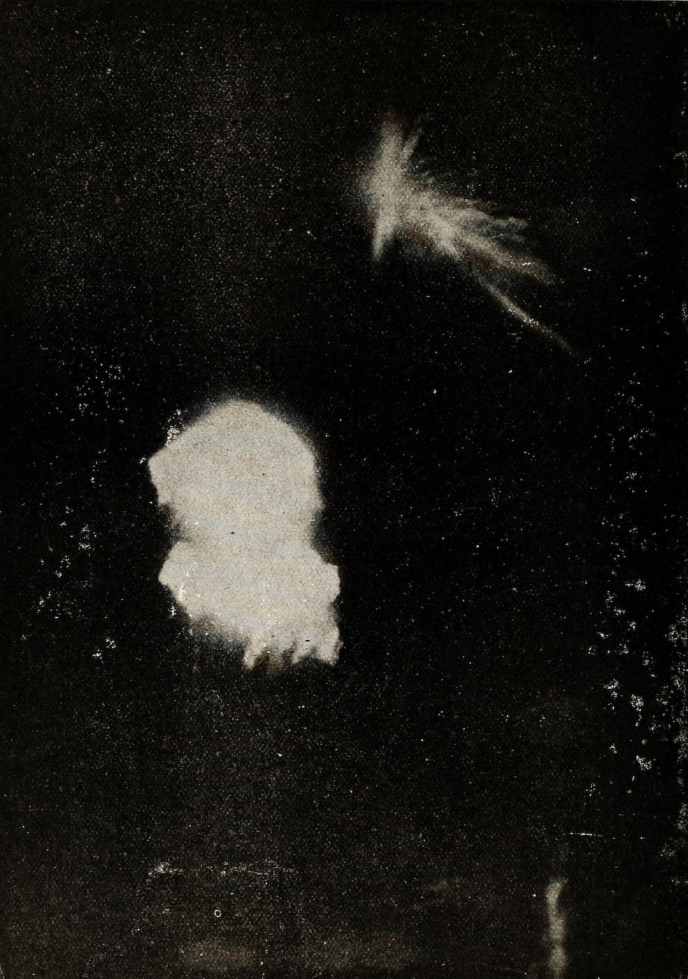 Black and white photograph of an explosion with a large central burst and smaller debris streaks against a dark background.